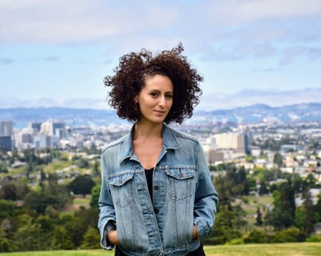 Headshot of Liza Rose Cirolia standing outside in front of a cityscape